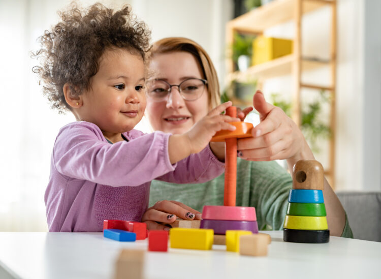 Child playing with a toy while an adult supports