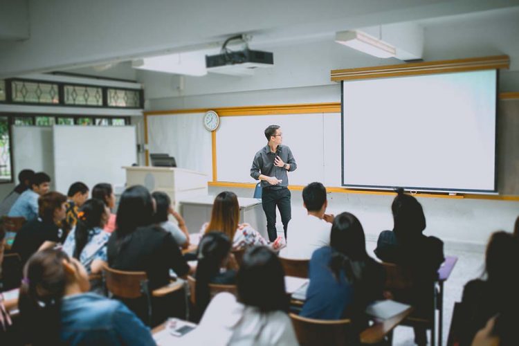 Teacher teaching students in classroom at university.